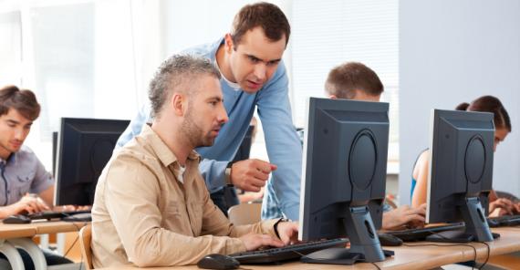 Man teaching someone how to use a computer