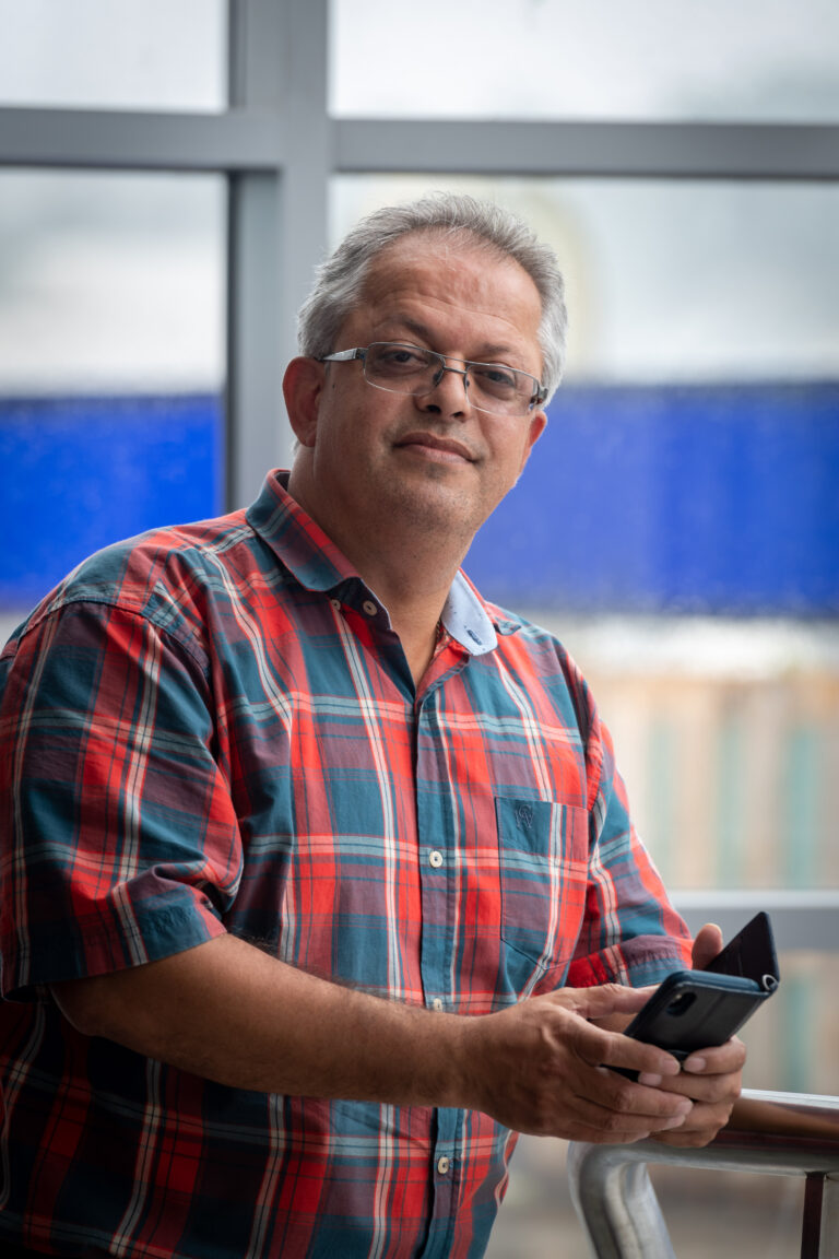 Shah, smiling whilst holding his phone