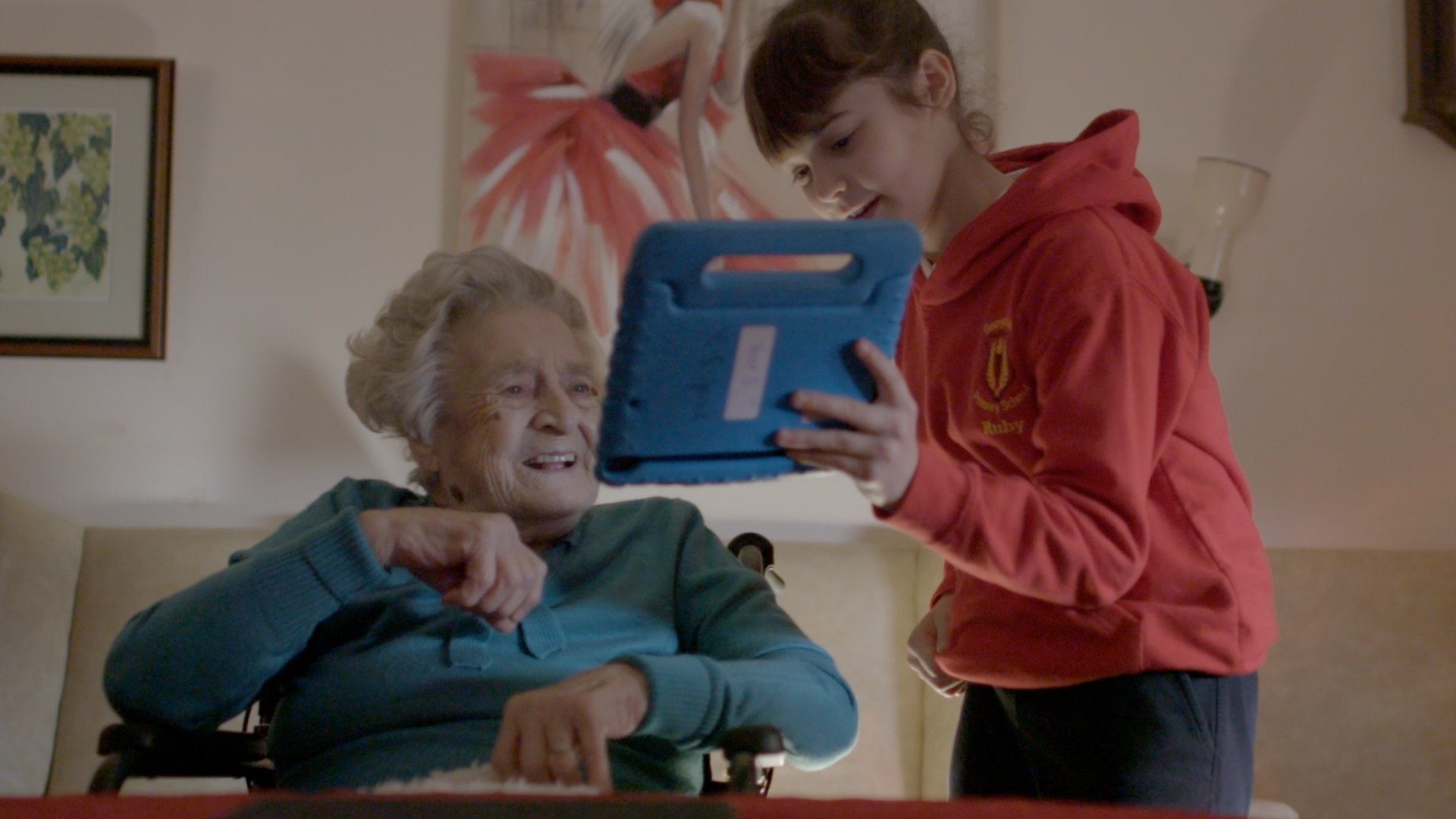 School pupil helping an older woman to use an iPad