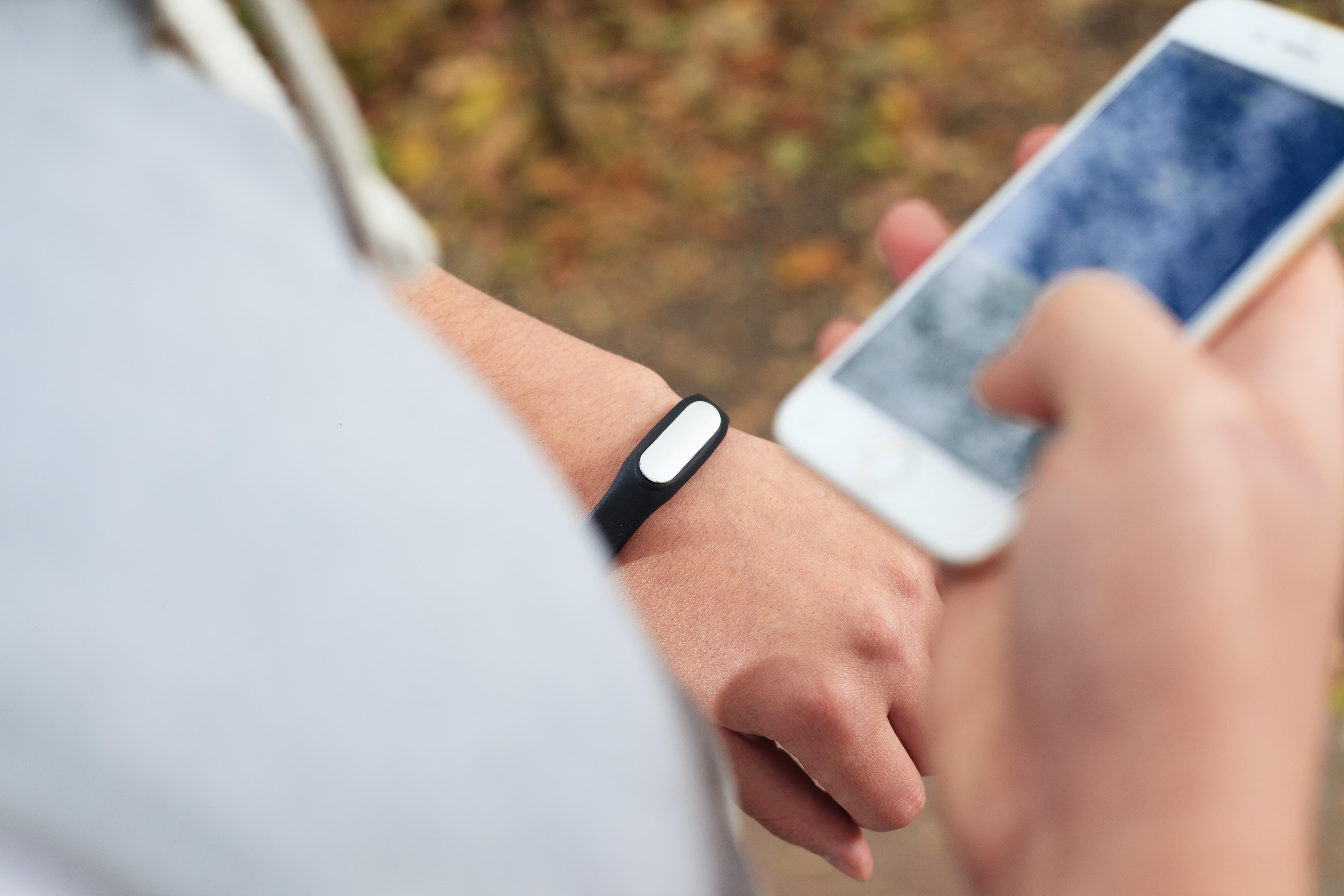 young woman using fitness bracelet during morning run